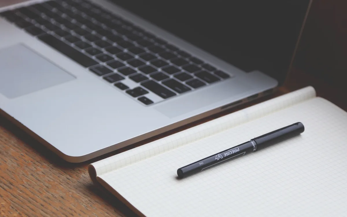 A writing desk with a laptop and notebook