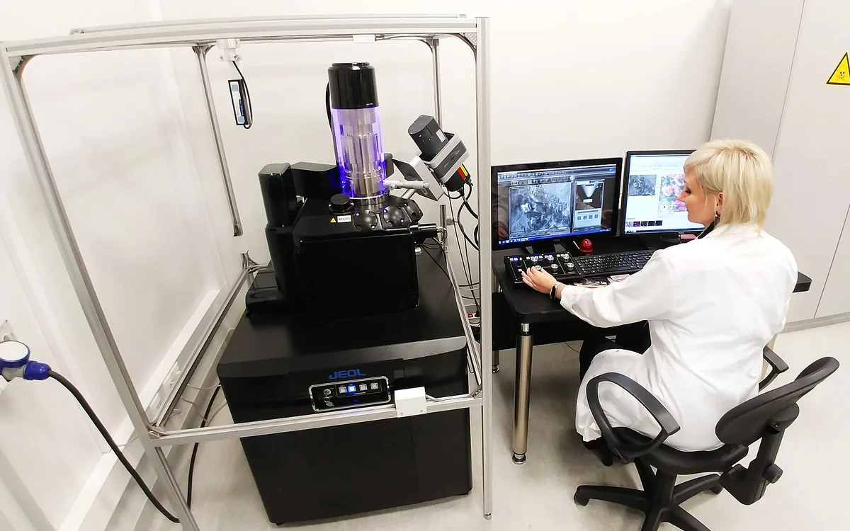 A scientist working with a scanning electron microscope in a laboratory.