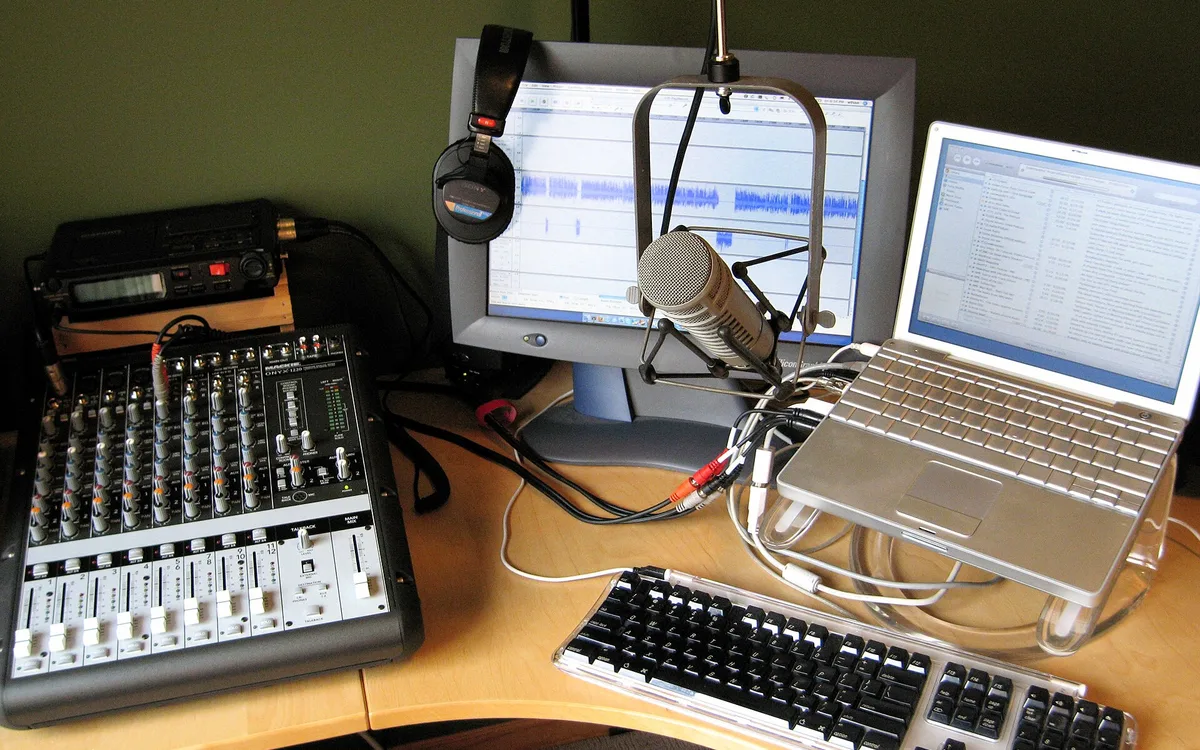 A compact home podcast studio with microphones, headphones, and recording gear.