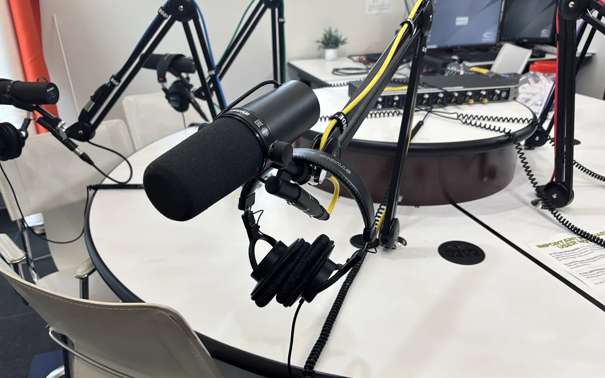 Podcast studio microphones arranged on adjustable arms in a recording room.