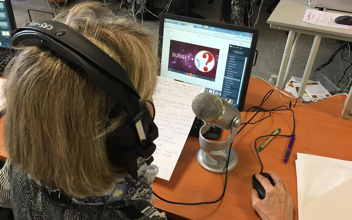A podcast recording setup seen from behind headphones, a microphone, and a script.